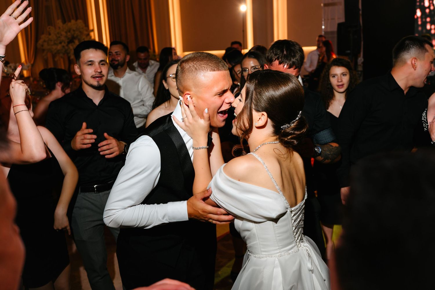 Bride and groom share a romantic dance together at their wedding reception surrounded by guests.