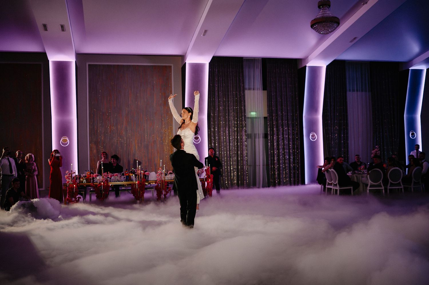Bride and groom share romantic first dance surrounded by dramatic dry ice fog cloud effect at wedding.