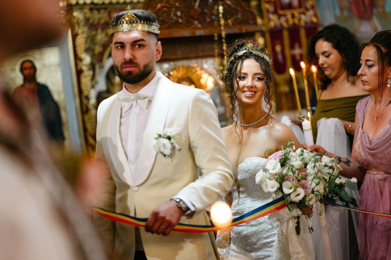 Bride and groom stand at church altar during Orthodox wedding ceremony, bride holding bouquet.