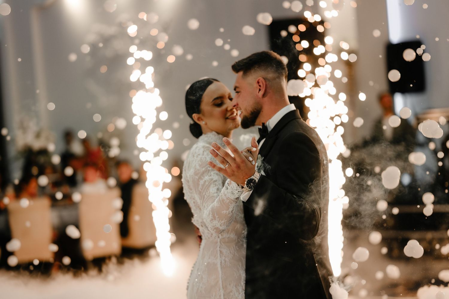 Bride and groom share first dance surrounded by sparkling wedding sparkler fountains indoors.