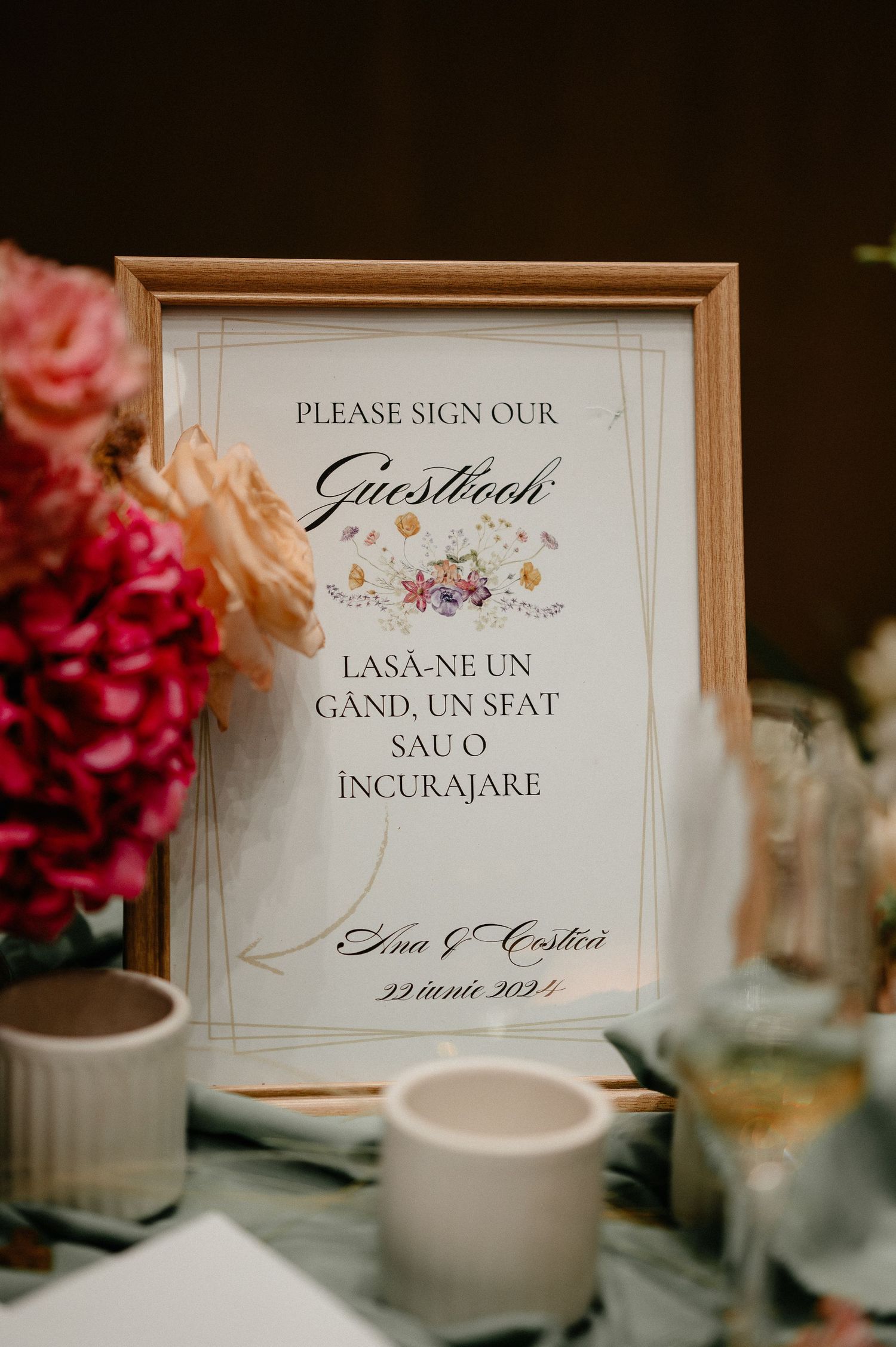 Framed bilingual guestbook sign for Ana and Costica wedding dated 22 iunie 2024 with flowers.