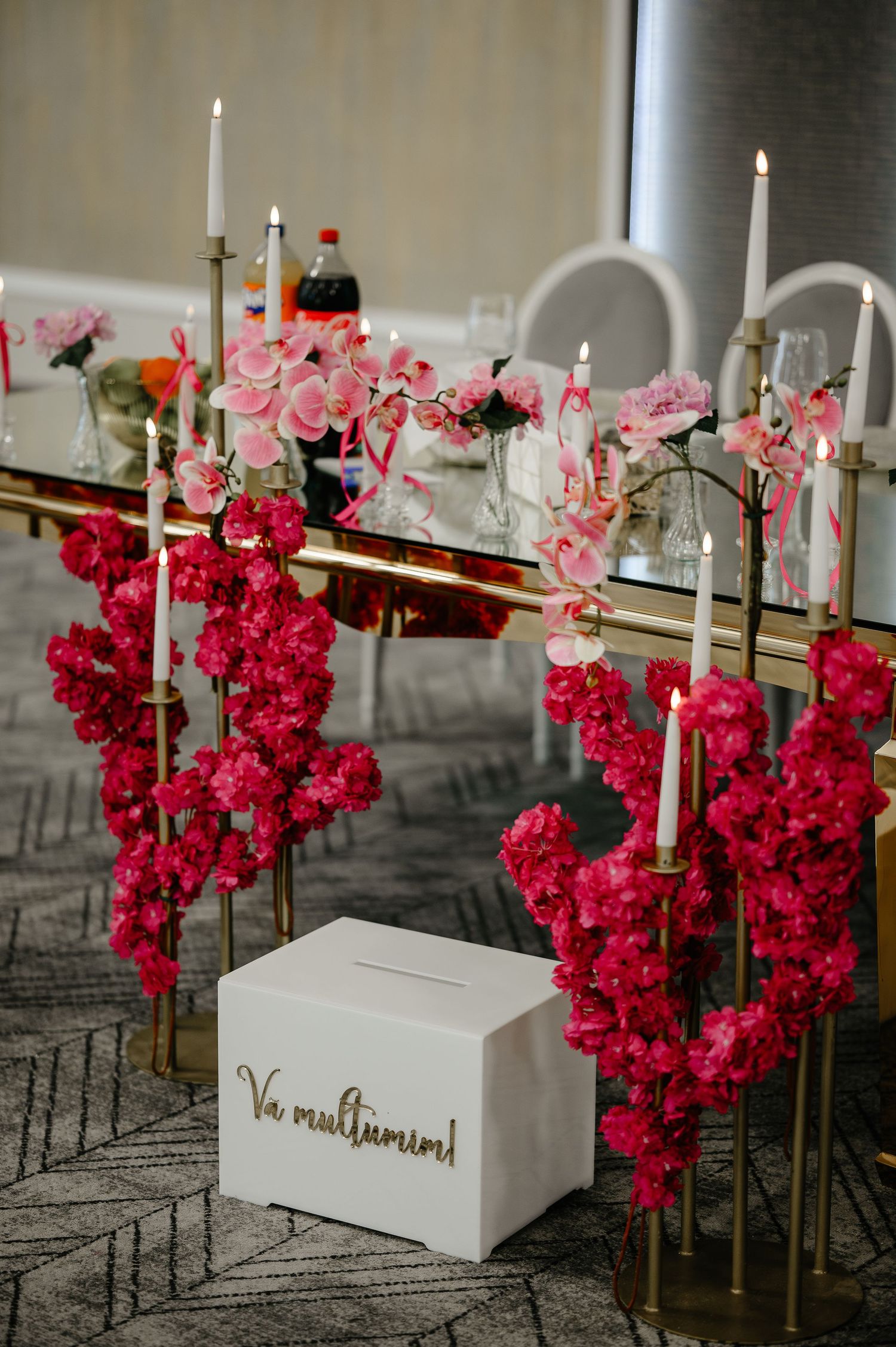 Wedding reception table with fuchsia floral garlands, white candles, and gift card box.