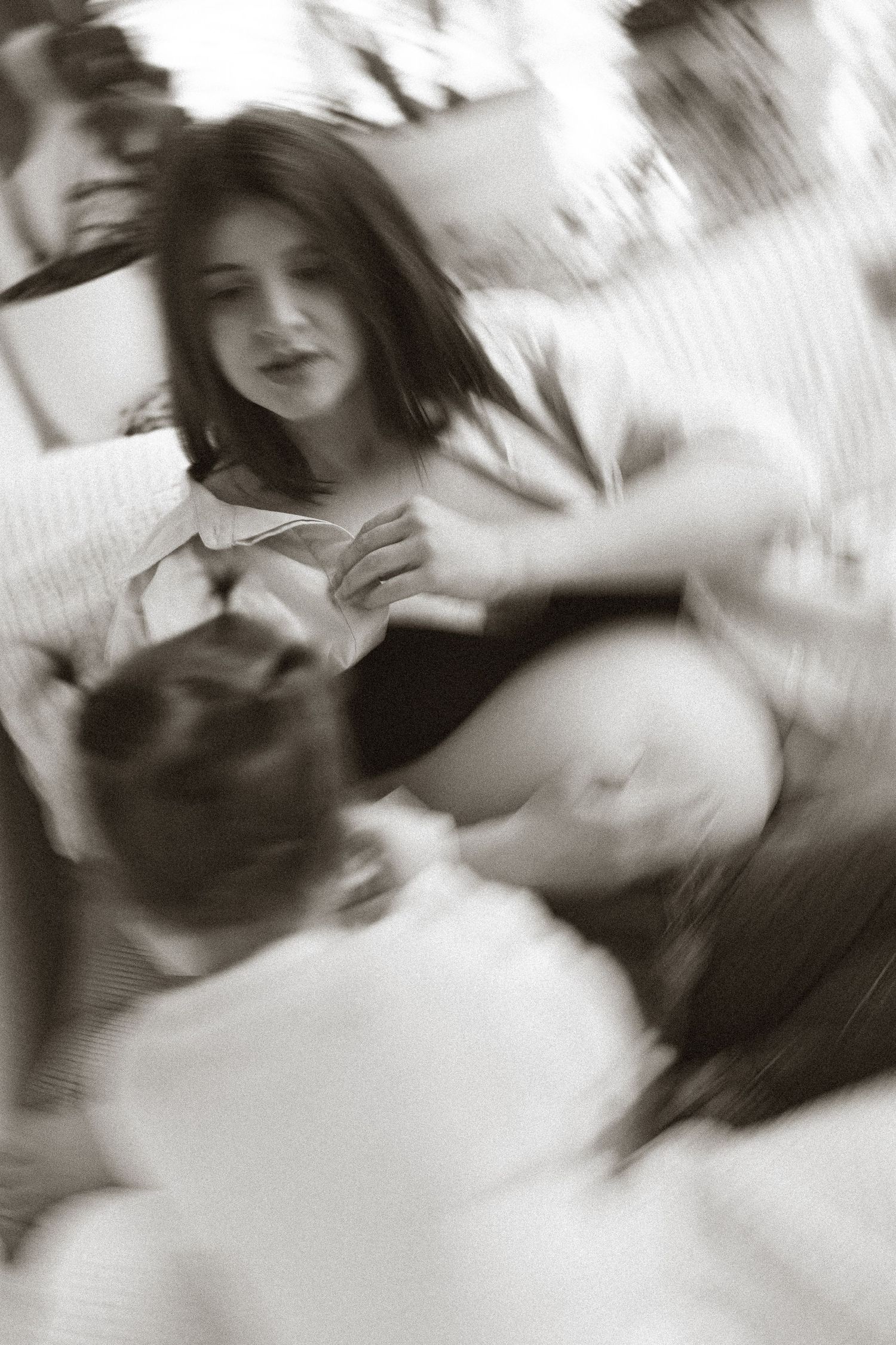 Black and white blurred photo of pregnant woman interacting with child on couch.