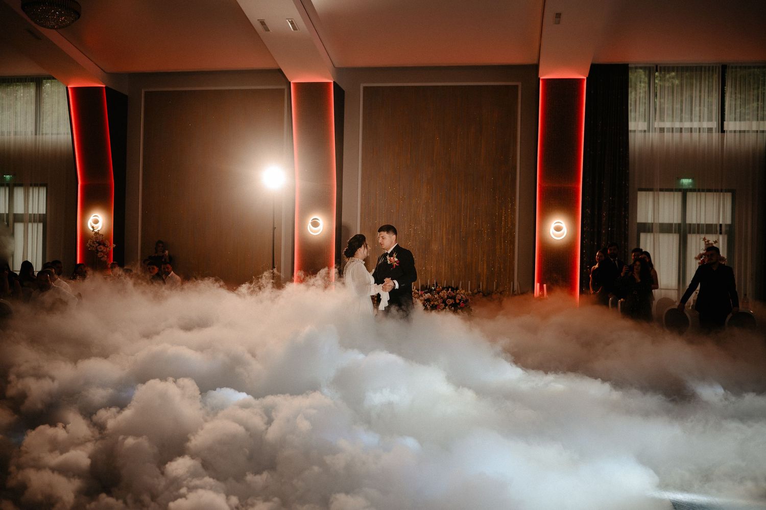 Bride and groom share first dance surrounded by dramatic dry ice fog on dance floor.