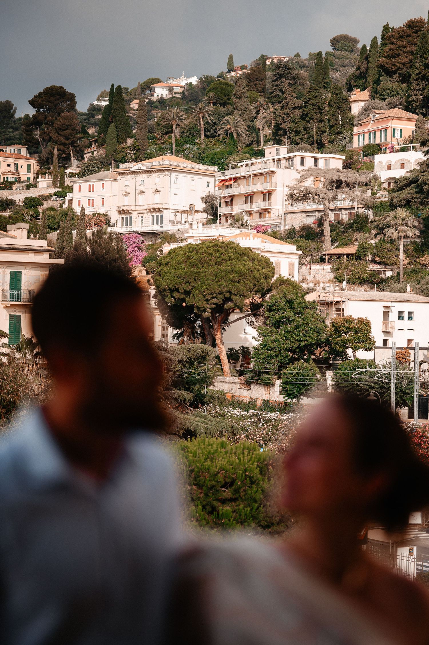 Blurred couple in foreground with scenic Italian hillside village buildings in background.