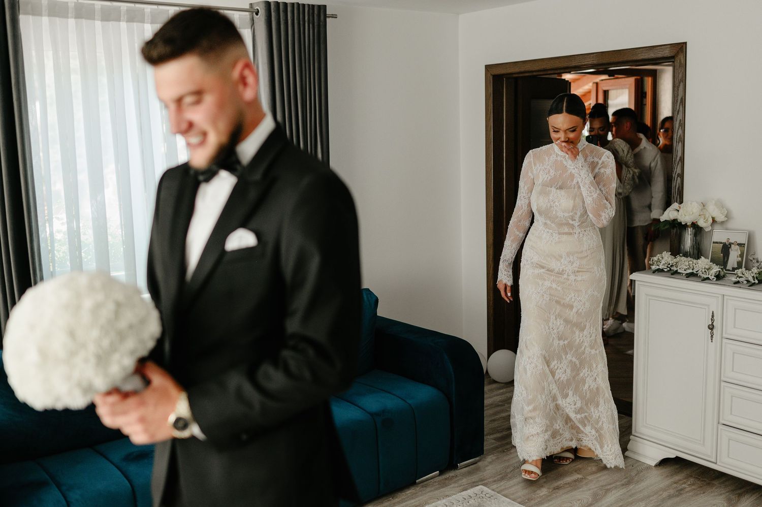 Bride in long sleeve lace wedding gown walking toward groom during first look reveal.