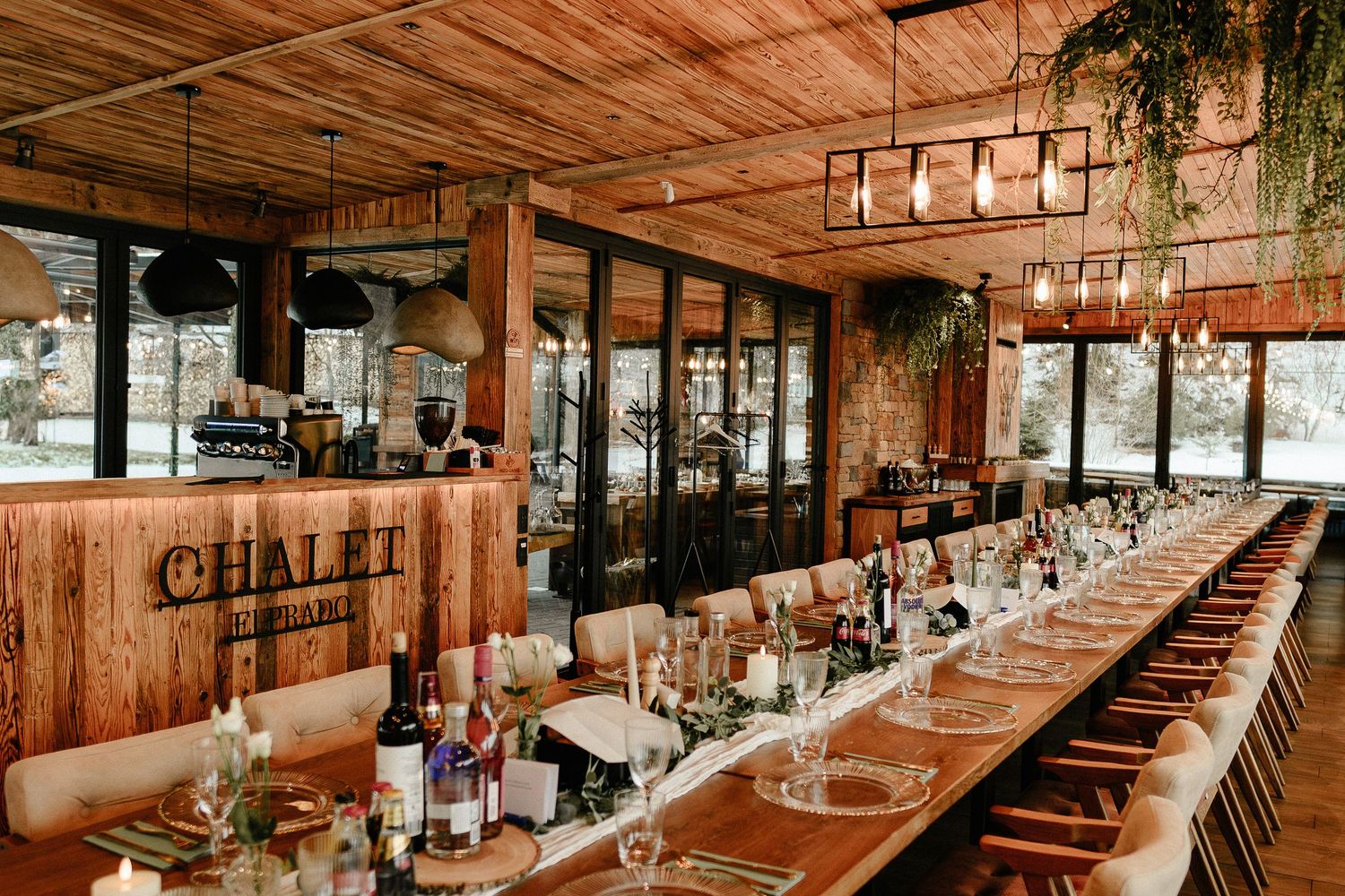 Elegant long banquet table set for a wedding reception inside a rustic wooden chalet restaurant.