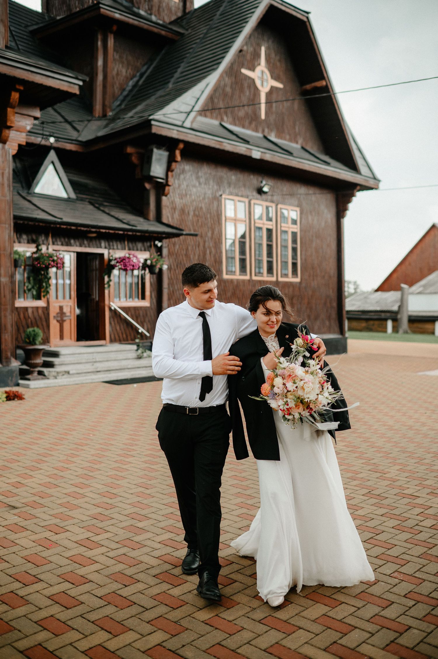 Bride and groom walking outside rustic wooden church after ceremony.