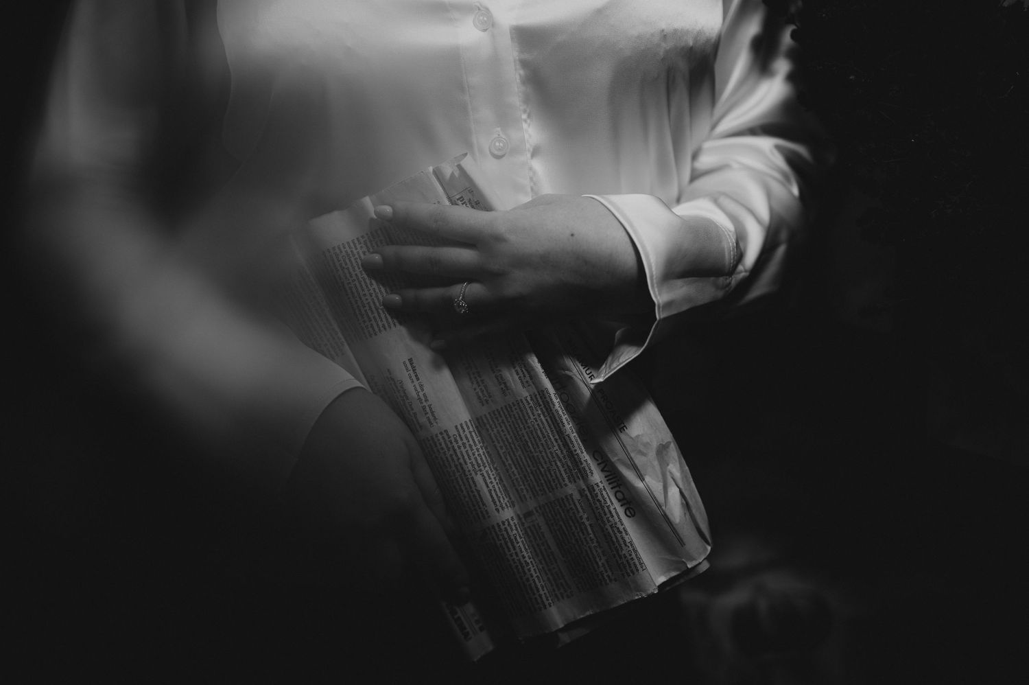 Black and white close-up of hands holding a plaid gift box at a formal event.