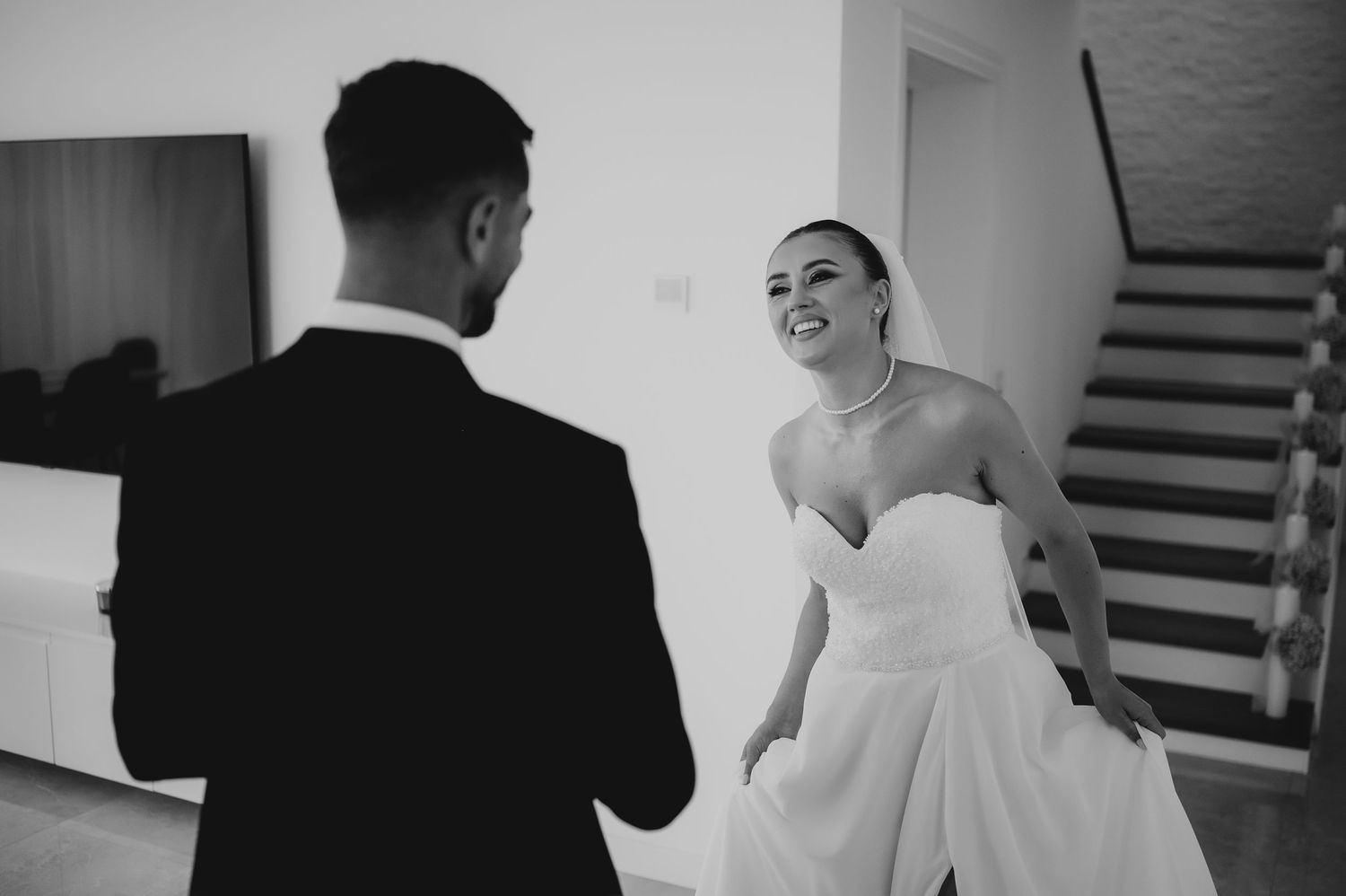 Black and white photo of bride smiling joyfully at groom during an intimate first look moment.