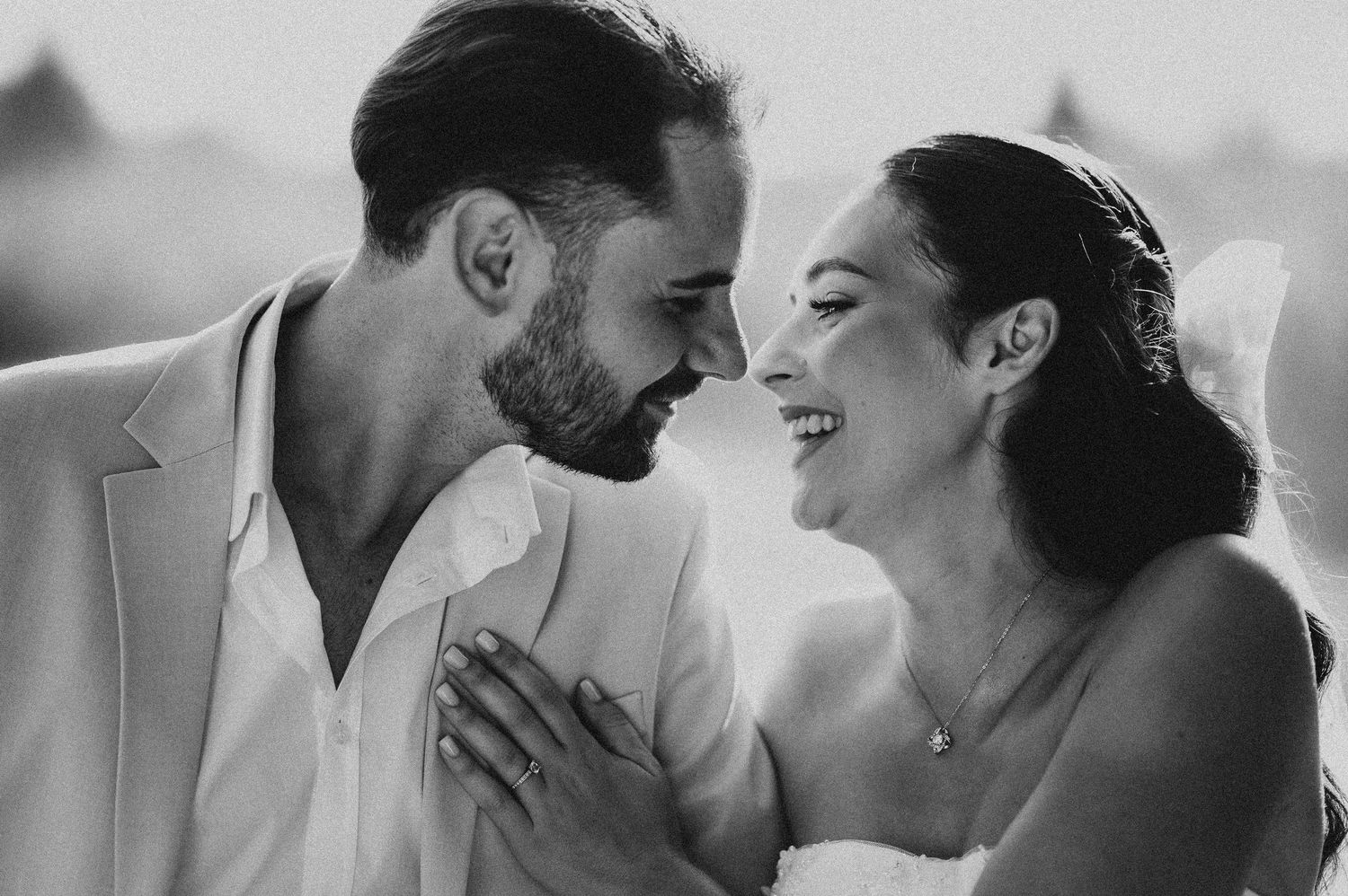Black and white photo of smiling bride and groom sharing an intimate moment on their wedding day.