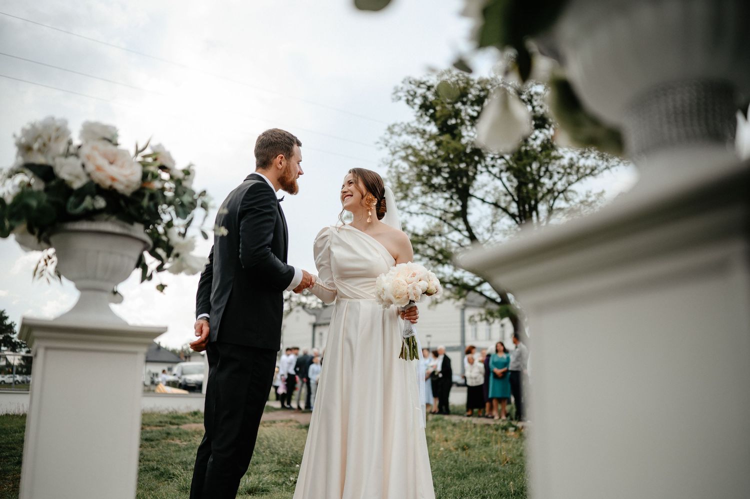 Bride and groom exchange vows at elegant outdoor wedding ceremony with white column decor.