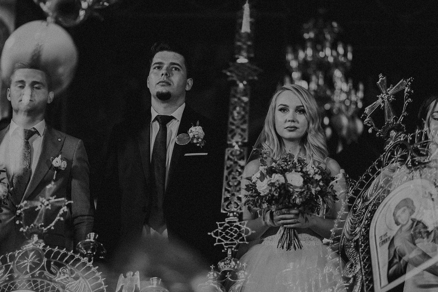 Black and white photo of bride and groom at Orthodox church wedding ceremony.