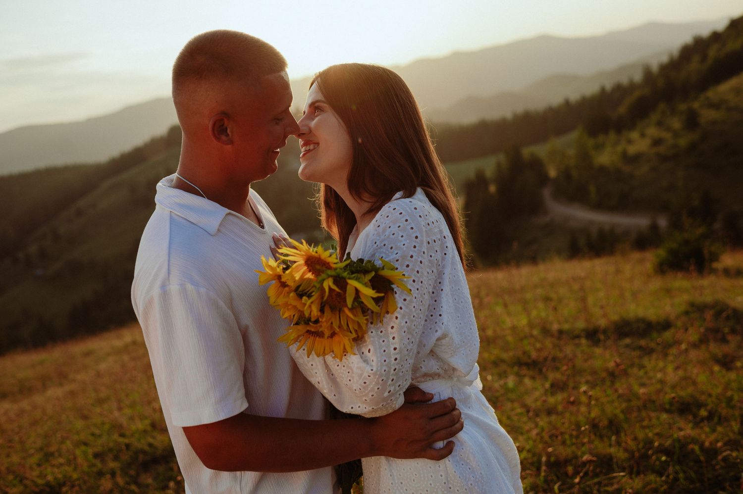 Loving couple sharing a tender moment nose-to-nose at golden hour with mountain backdrop.