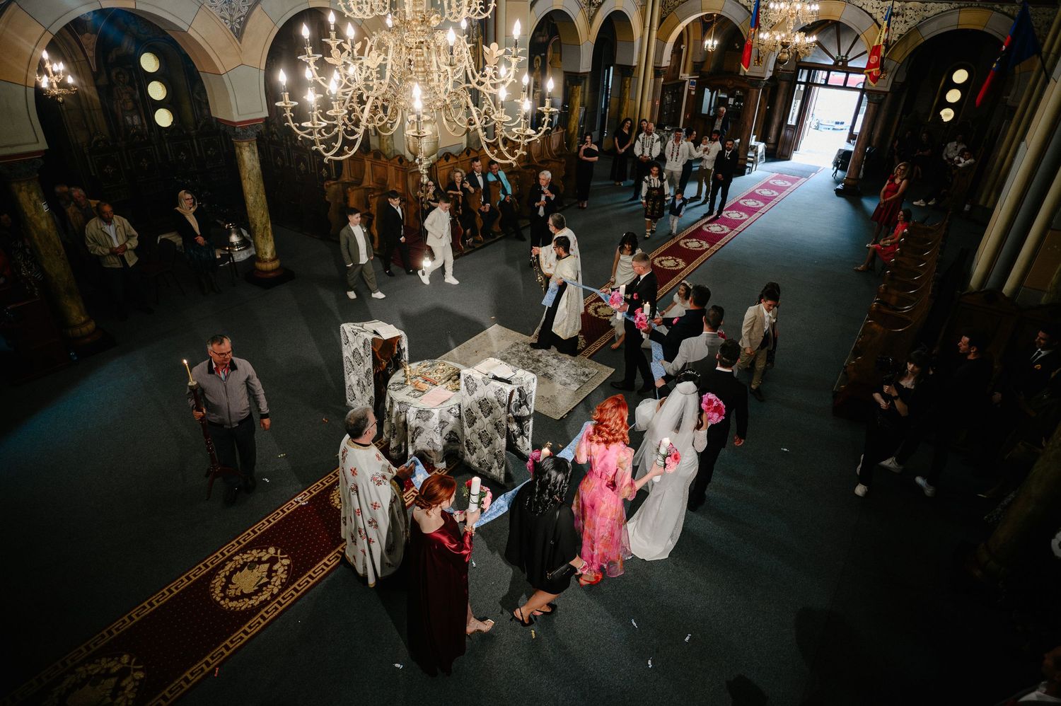 Aerial view of an Orthodox church wedding ceremony with guests gathered in an ornate interior.