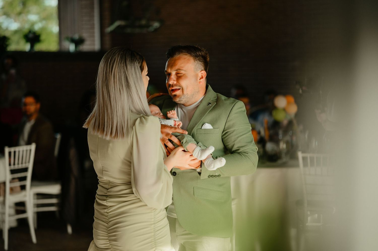 Couple in sage green outfits sharing a tender dance moment at an elegant indoor event.