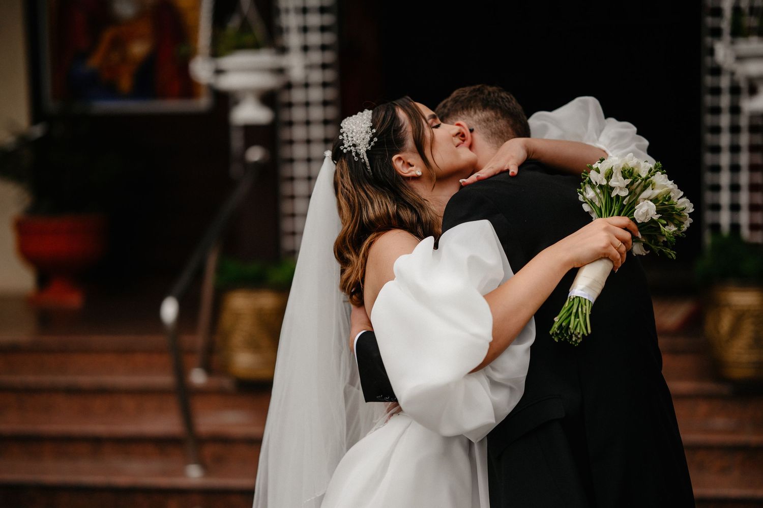 Bride and groom sharing first kiss at church entrance on their wedding day.