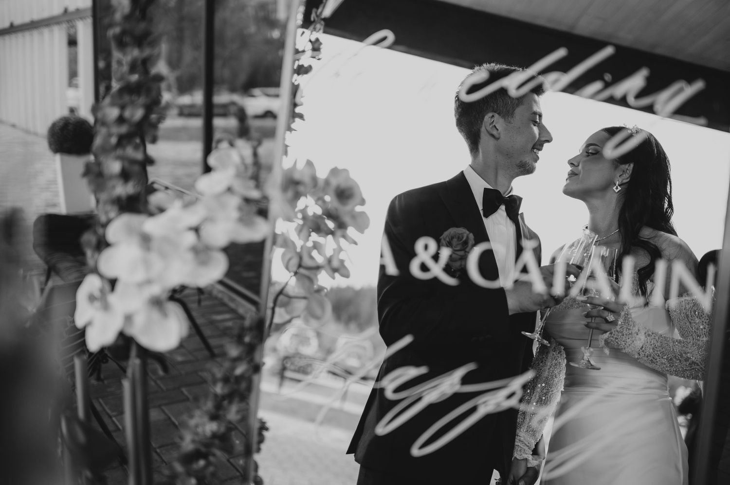 Black and white romantic wedding photo of bride and groom with cursive name overlay Ana and Catalin.