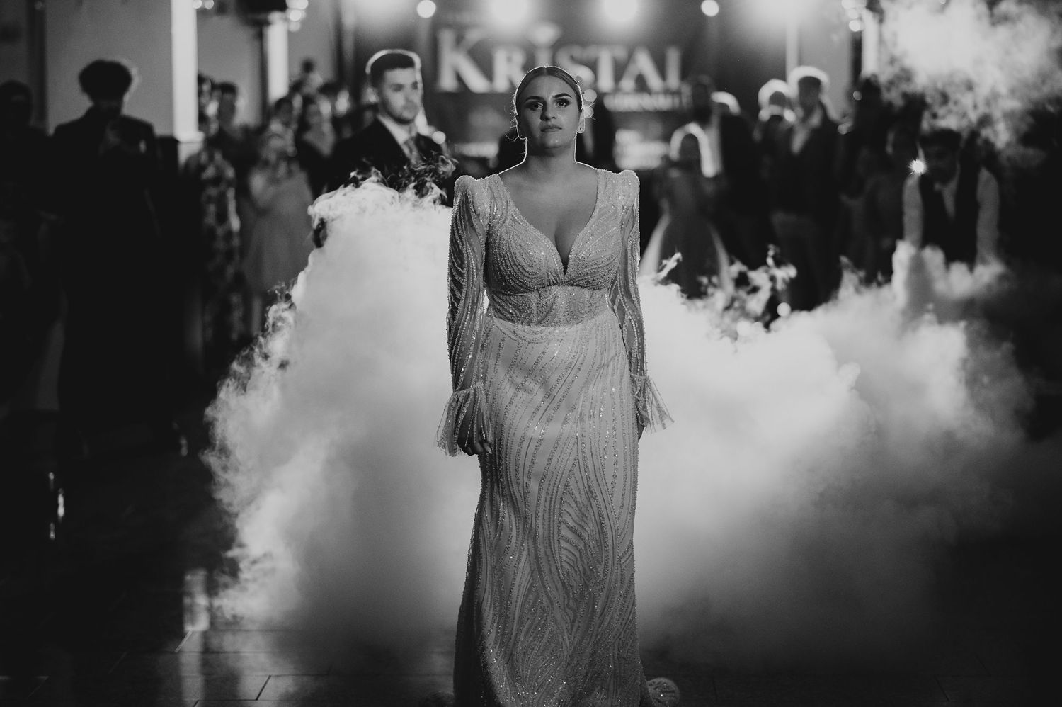 Bride makes dramatic entrance in beaded gown surrounded by fog machine smoke at Kristal wedding venue.