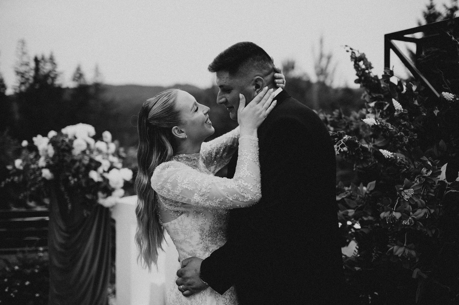 Black and white romantic photo of bride and groom sharing an intimate moment outdoors at dusk.