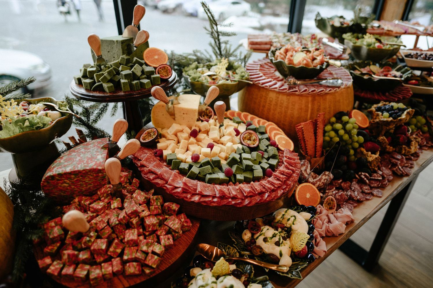 Elaborate charcuterie and appetizer display table with meats, cheeses, fruits, and garnishes at a catered event.