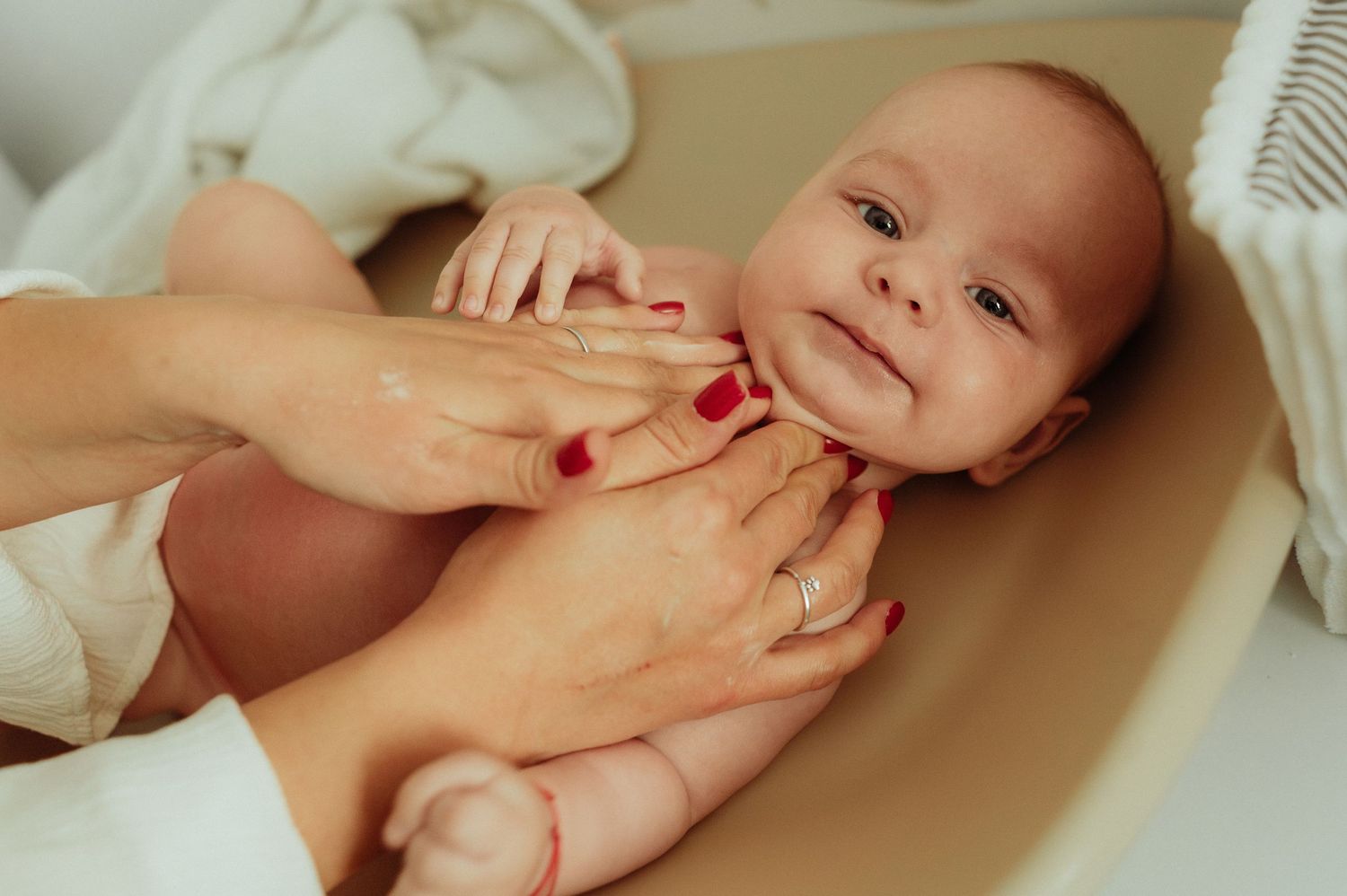 Close-up of newborn baby being gently held in hands during bath time.