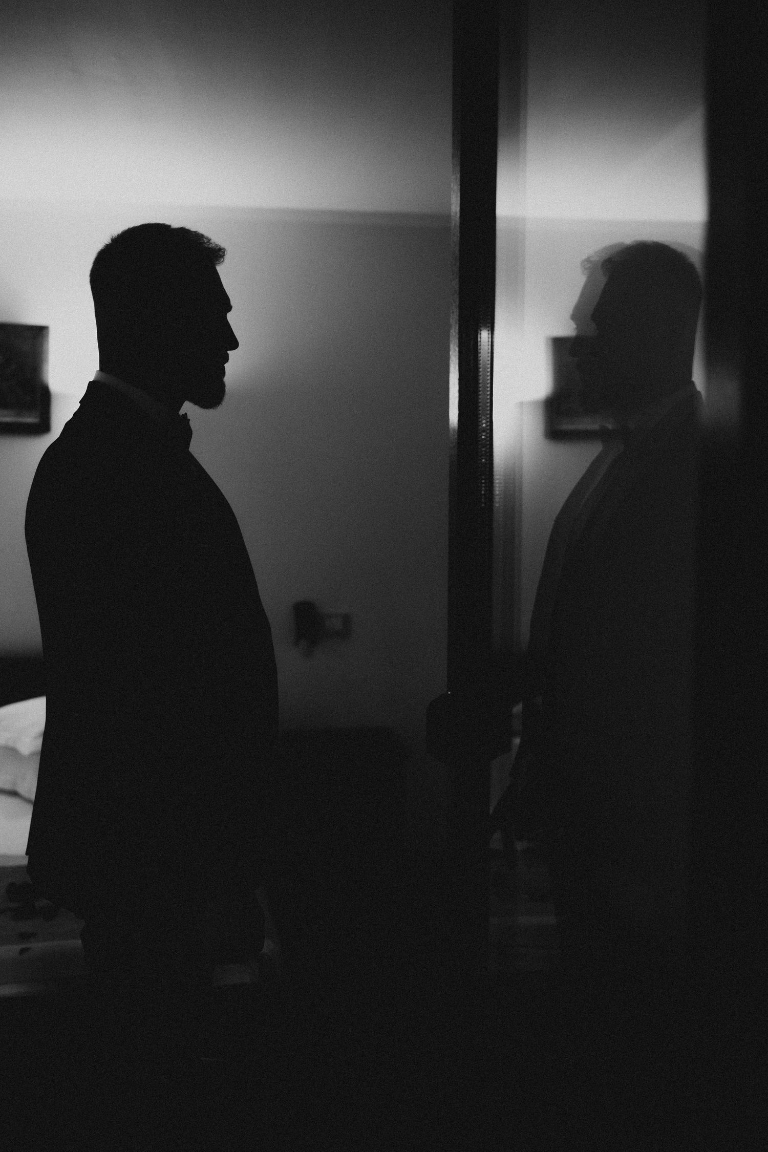 Black and white silhouette of two men facing each other in a dimly lit room, dramatic contrast lighting.