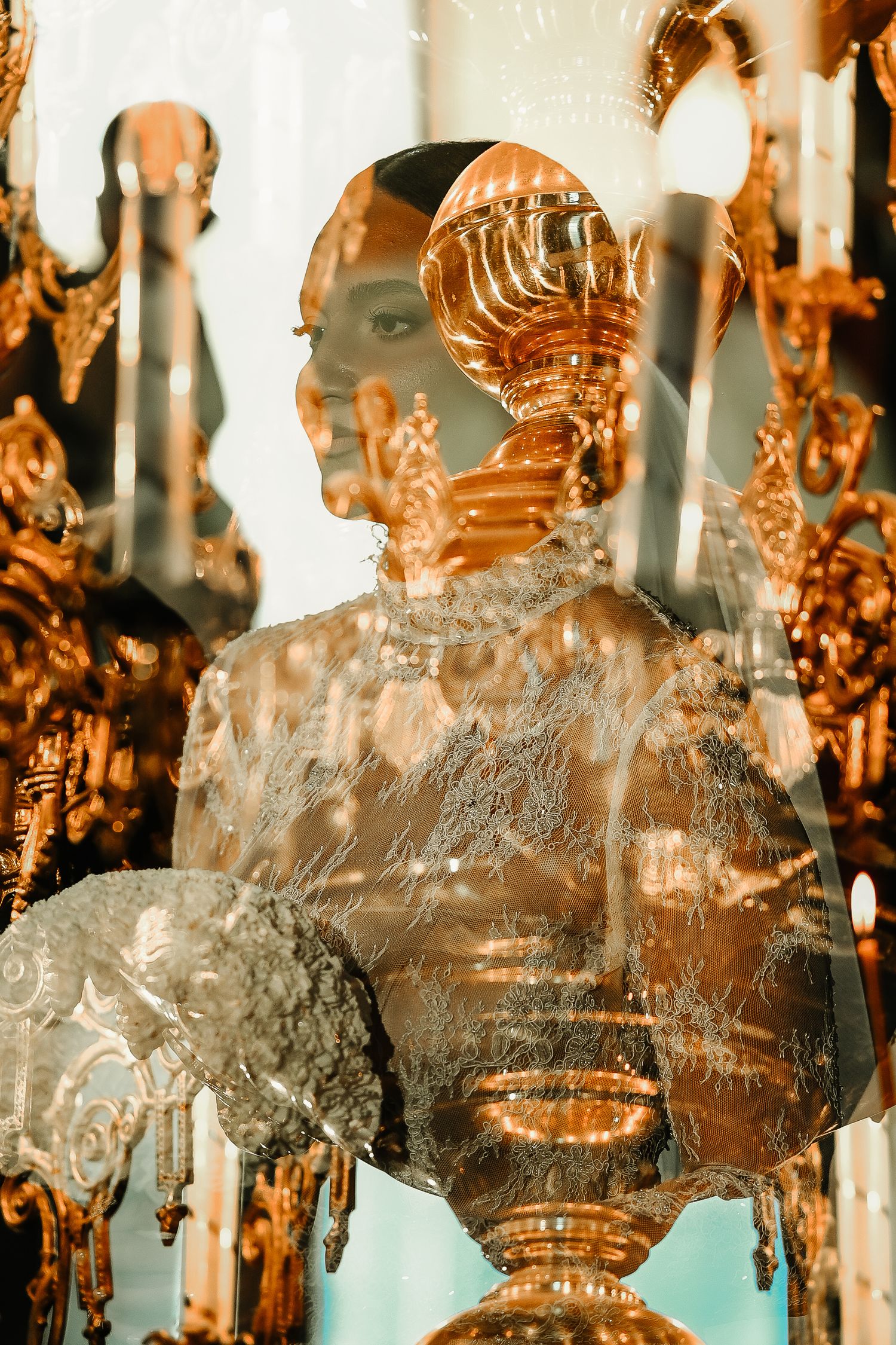 Artistic double exposure of bride reflected in golden church candelabra during ceremony.