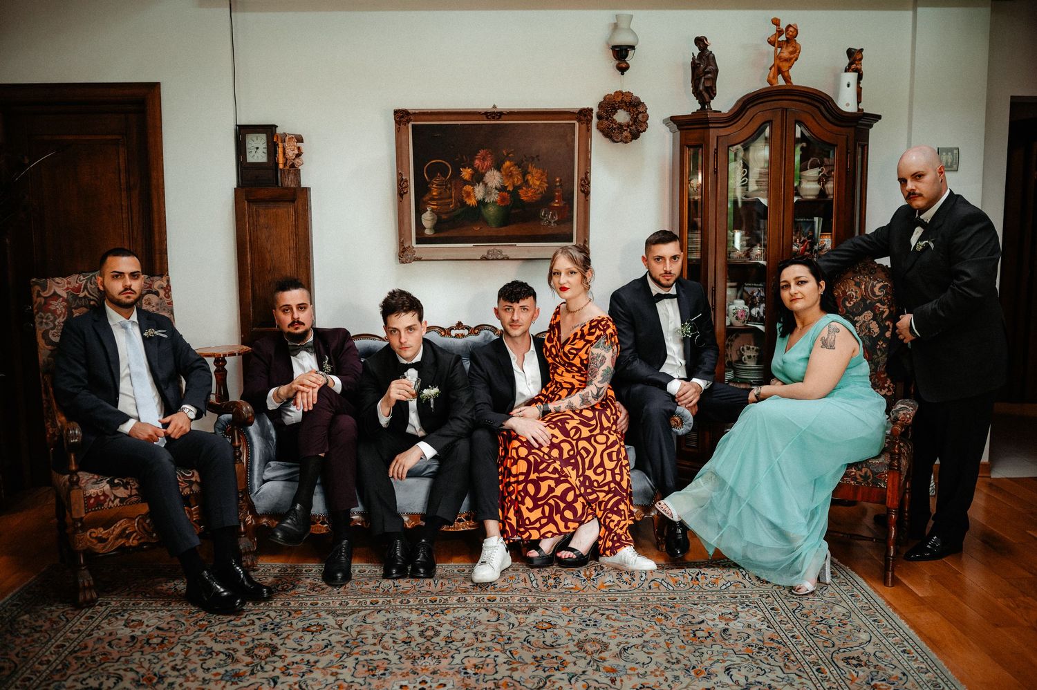 Wedding party group posed casually in an elegant vintage-furnished room with ornate decor and artwork.