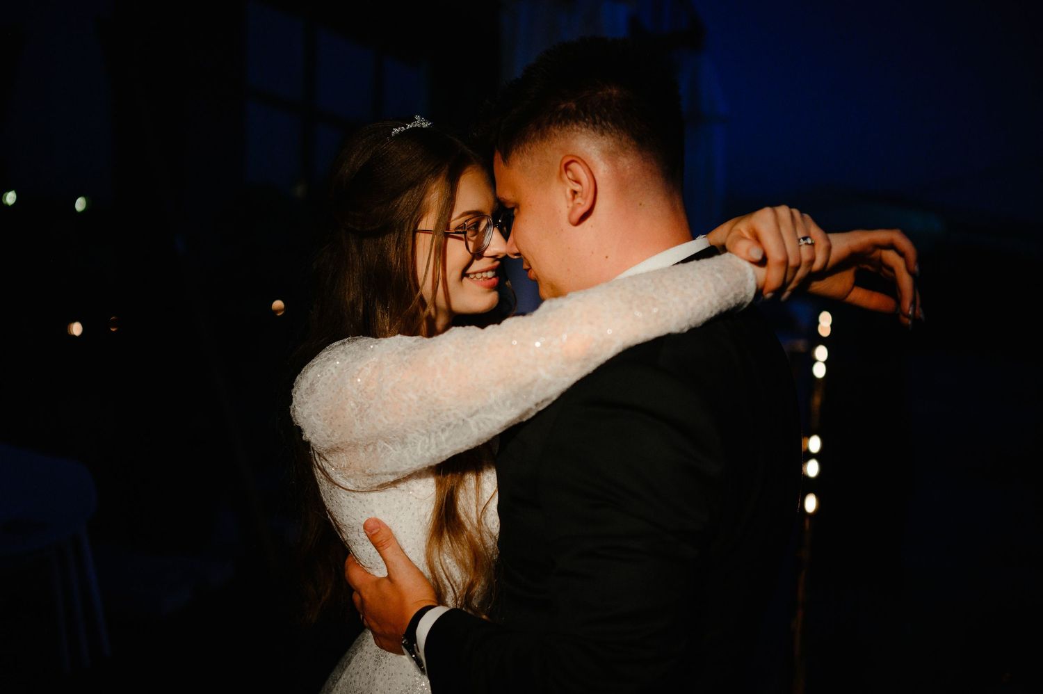 Bride and groom share a romantic dance embrace under soft evening lights at their wedding.