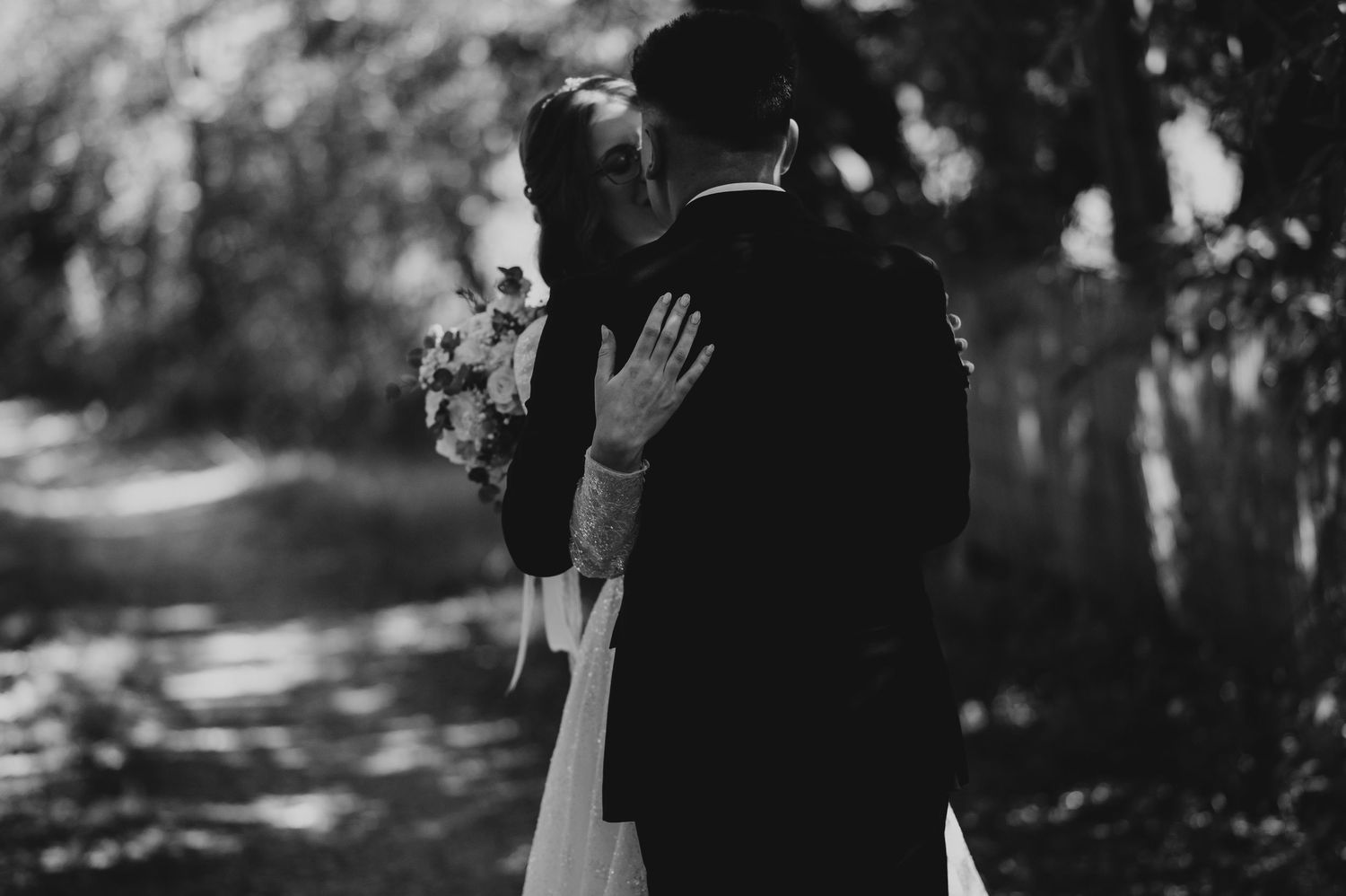 Bride and groom kissing in black and white portrait with soft bokeh background.