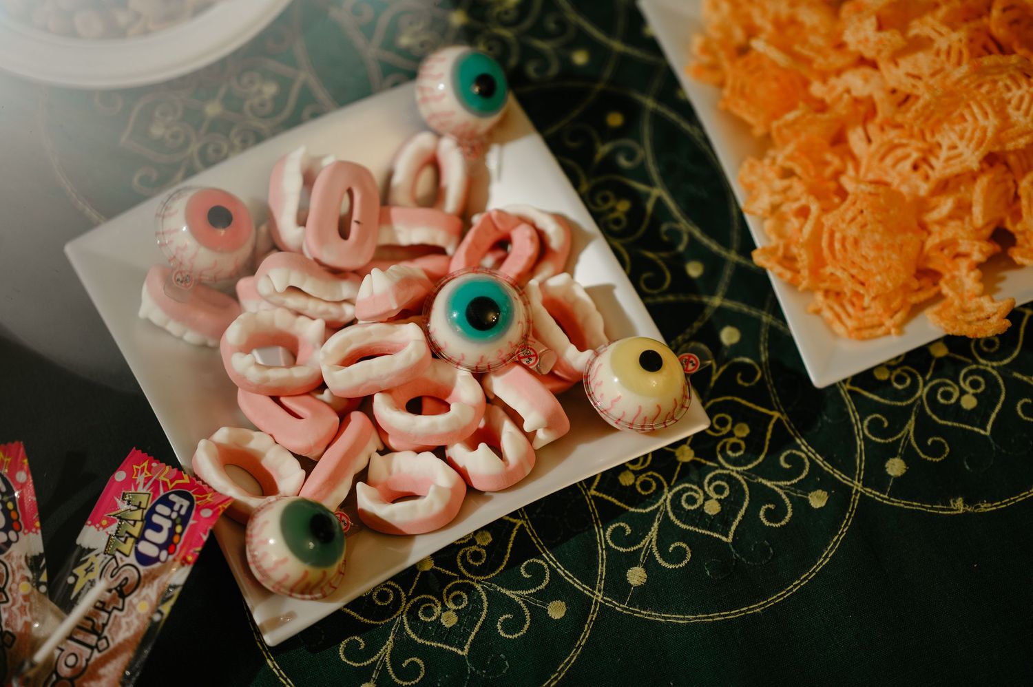 Halloween party snack table with gummy candy eyeballs and colorful treats on a platter.