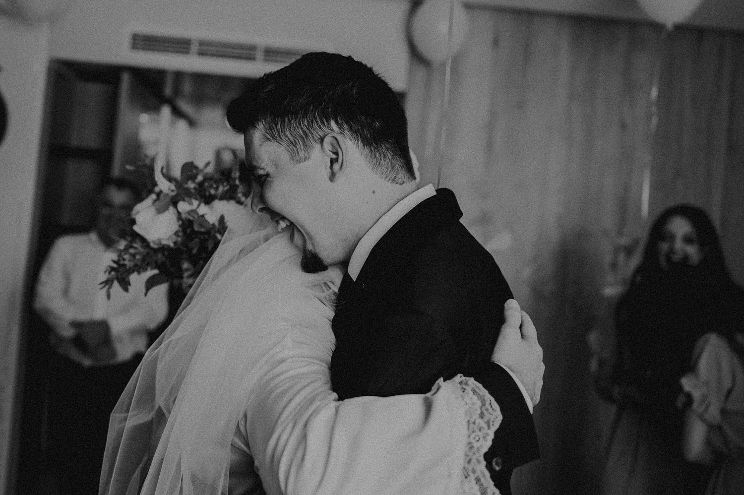 Emotional black and white photo of groom hugging bride tightly during heartfelt wedding first look.