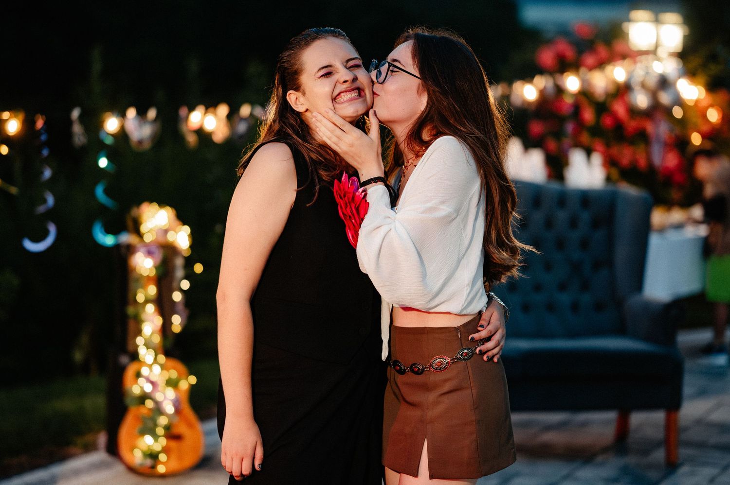 Two young women sharing a joyful moment embracing at a festive outdoor night event.