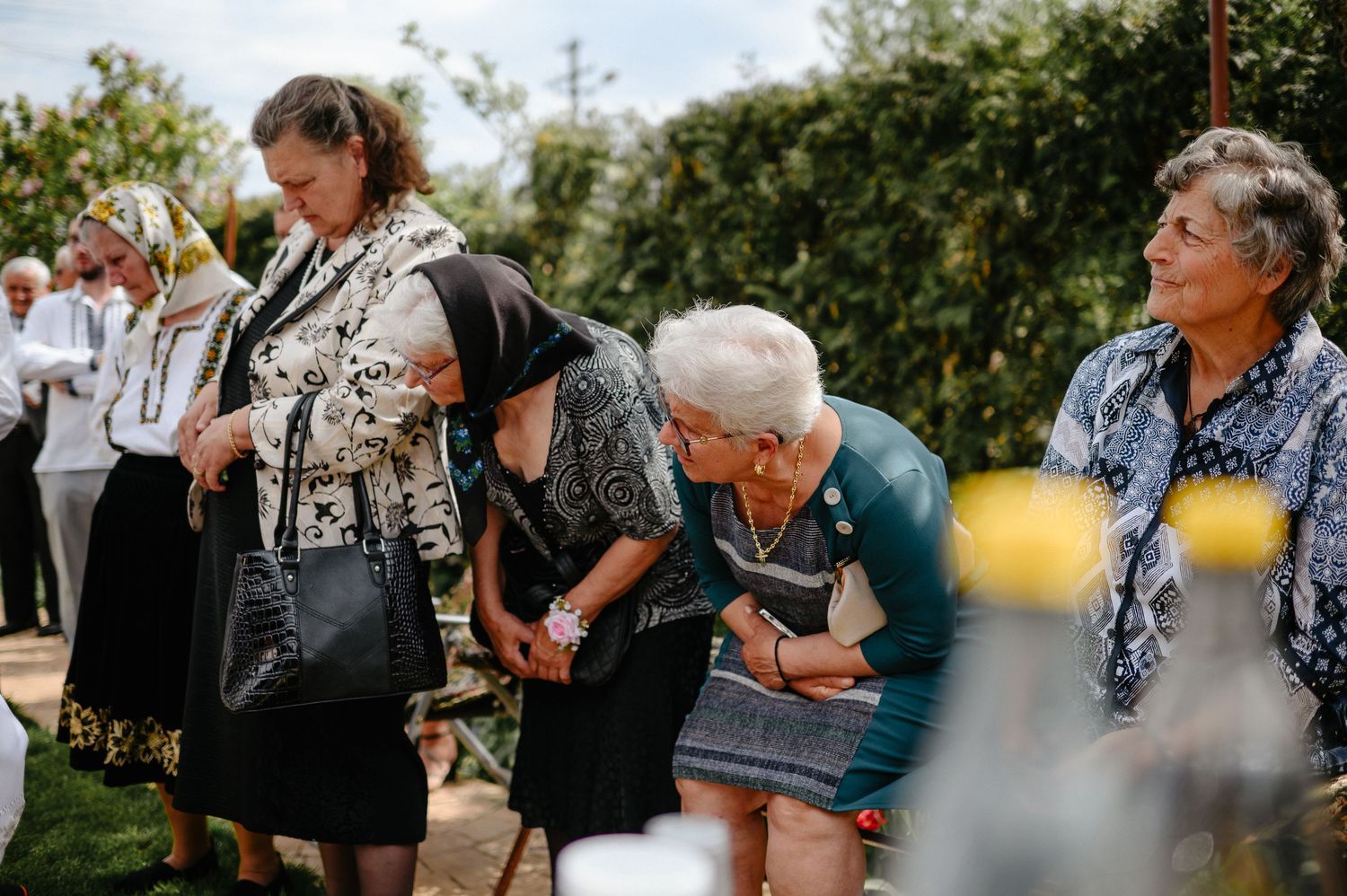 Group of elderly women in traditional attire gather and converse at an outdoor wedding celebration.