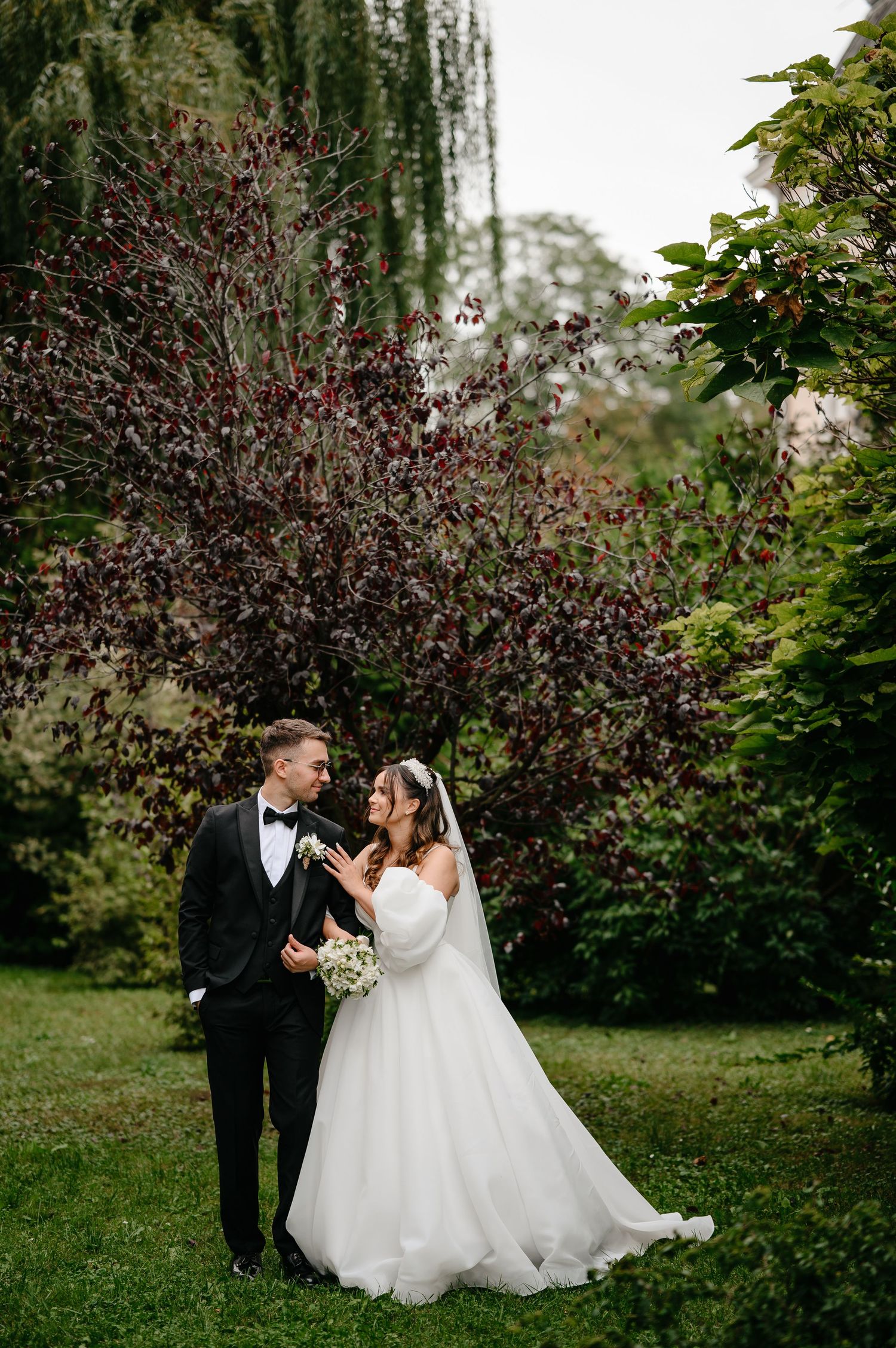 Wedding couple sharing a romantic moment in a garden with colorful autumn foliage backdrop.