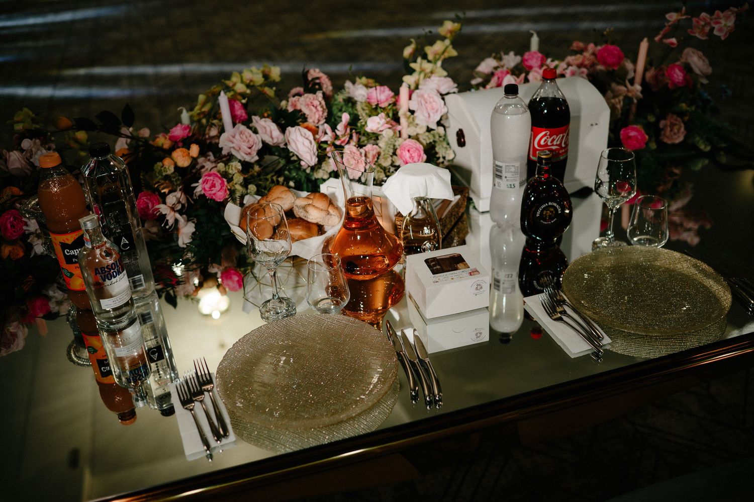 Elegant wedding table setting with pink florals, candles, and sparkling charger plates.