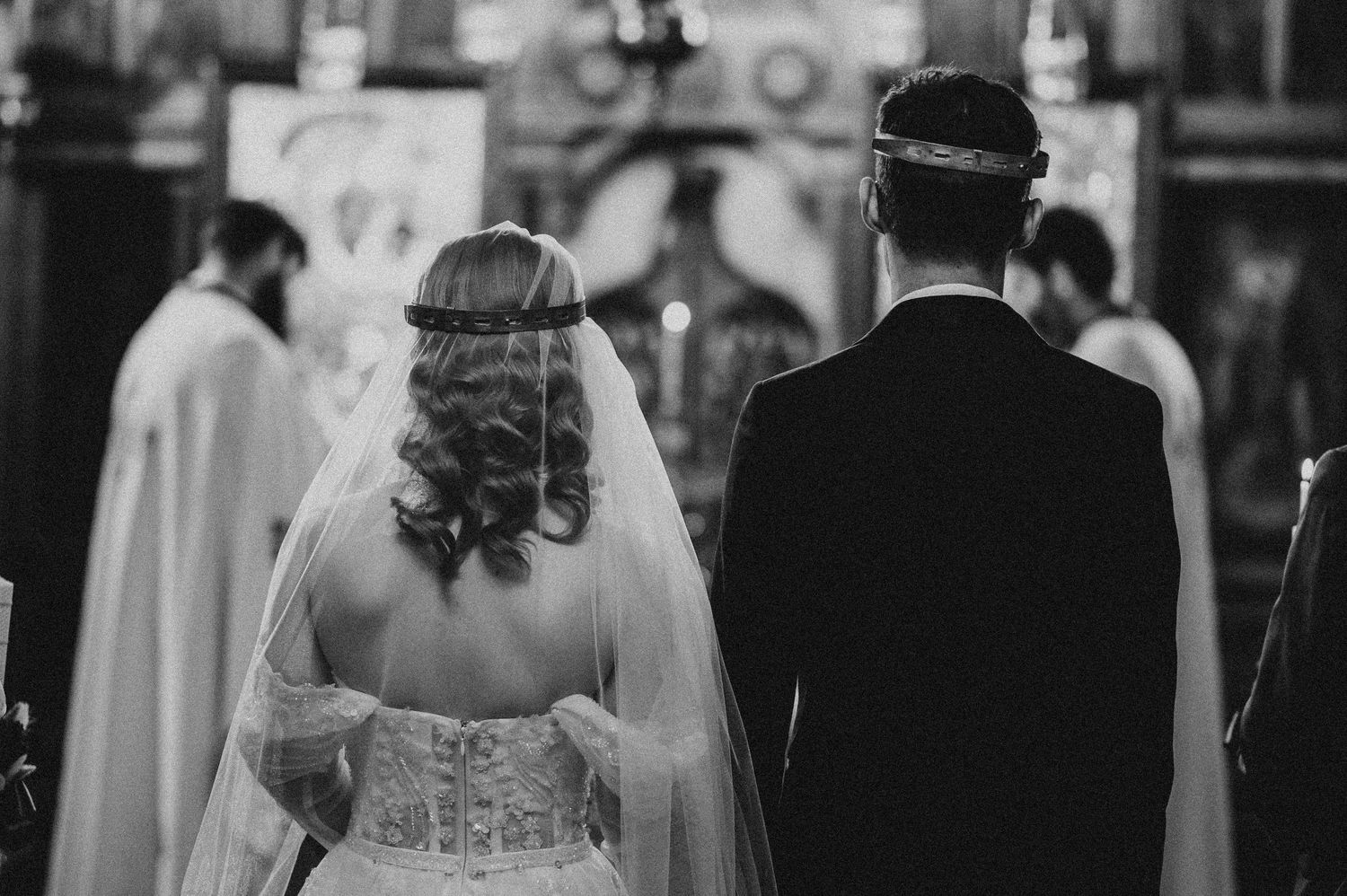 Black and white photo of bride and groom standing at church altar during wedding ceremony.