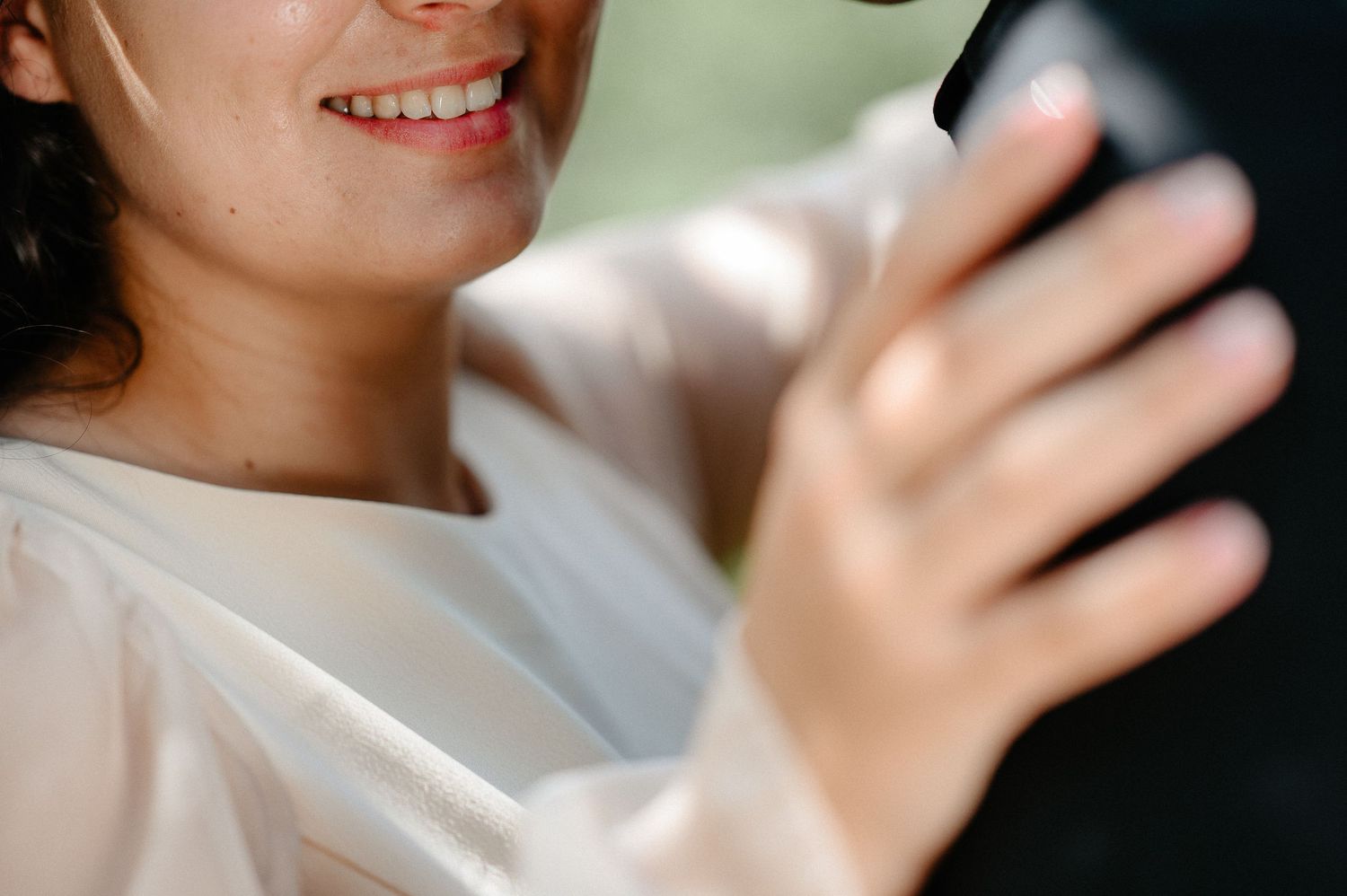 Smiling bride in white dress taking a selfie on her wedding day.
