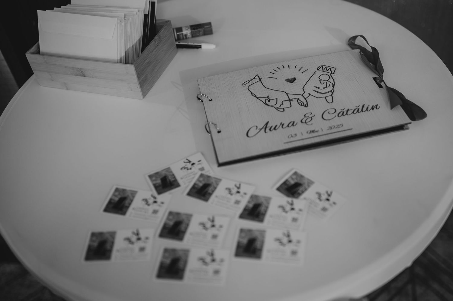 Black and white photo of wedding guestbook and polaroid photos on round table.