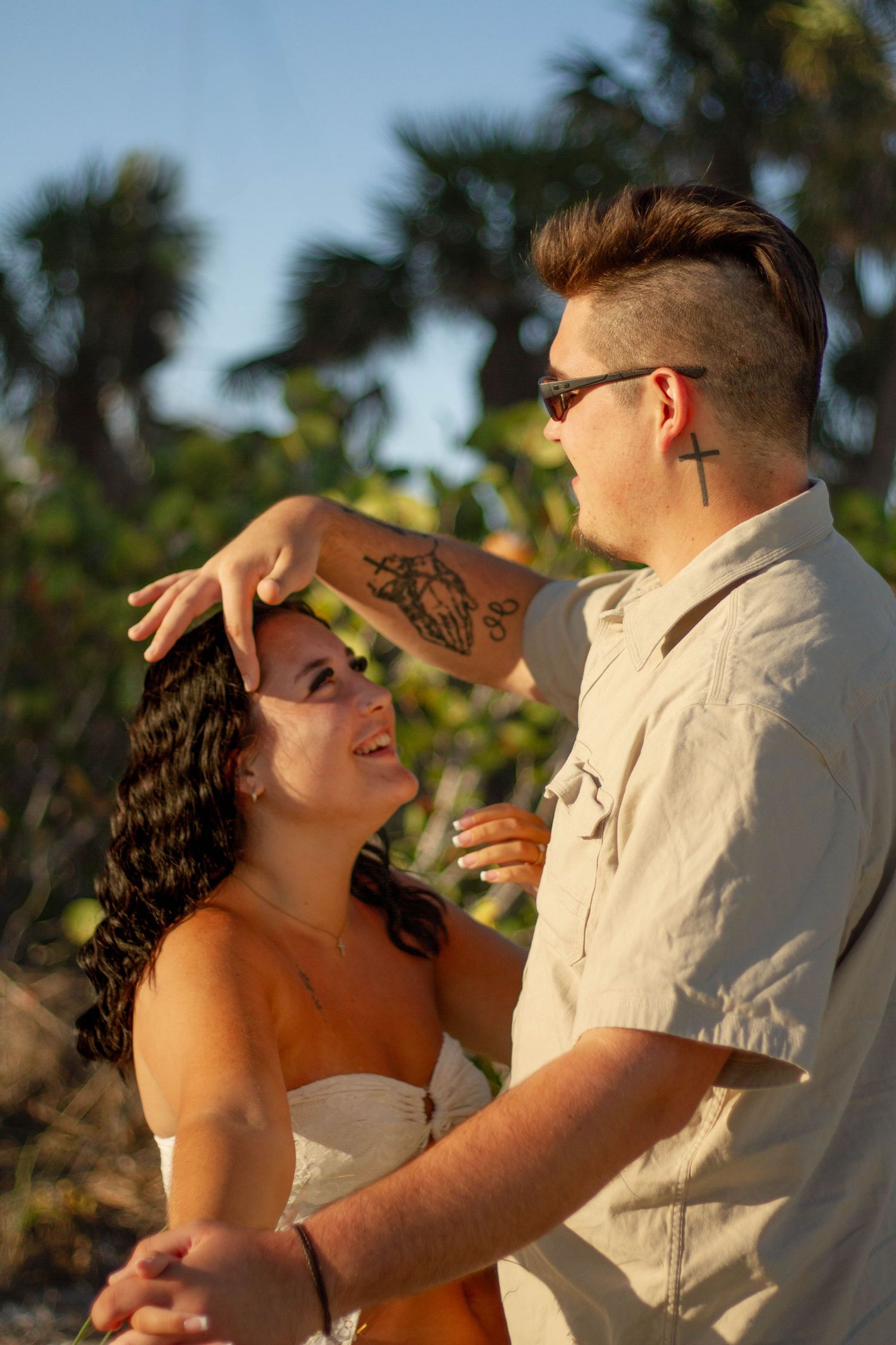 Couple gazing at each other and laughing near tropical palm trees outdoors.