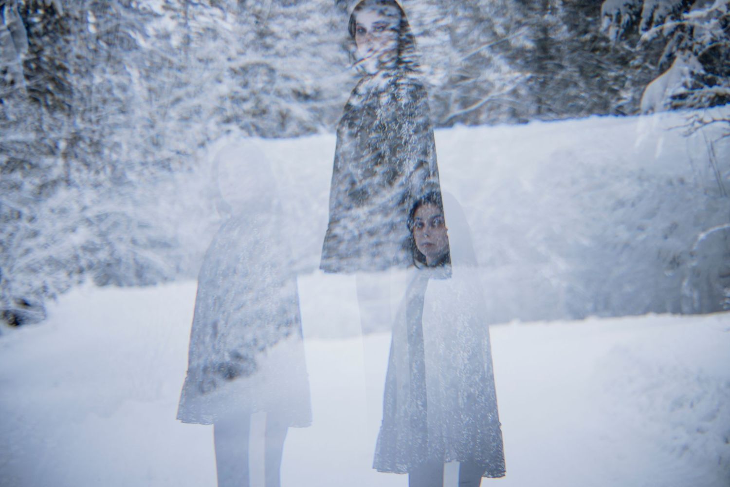 Double exposure portrait of a woman in snowy winter forest with ghostly overlay effect.