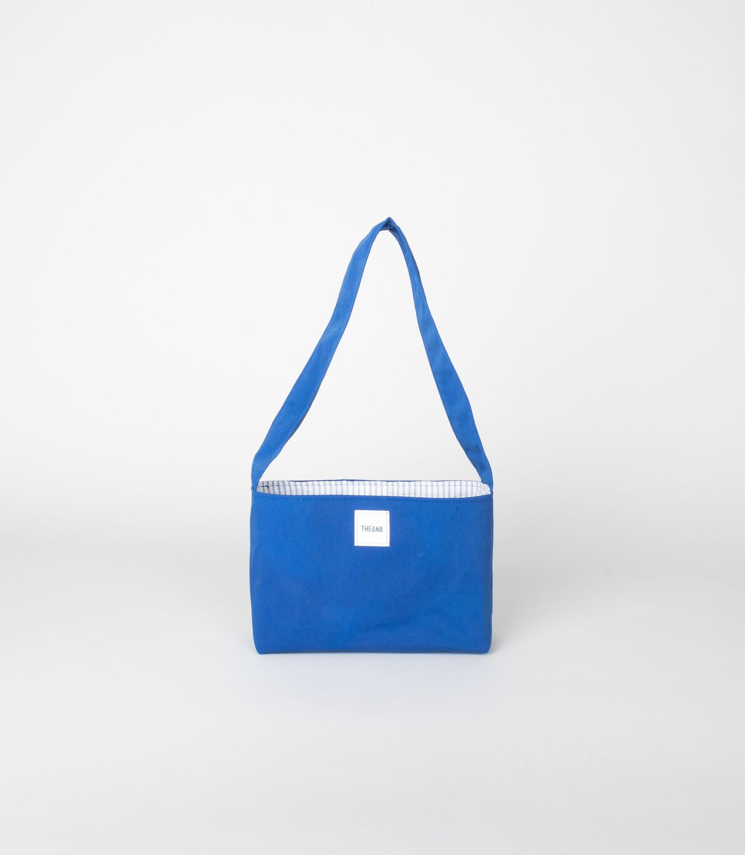 Bright blue canvas shoulder tote bag with striped interior and white label.