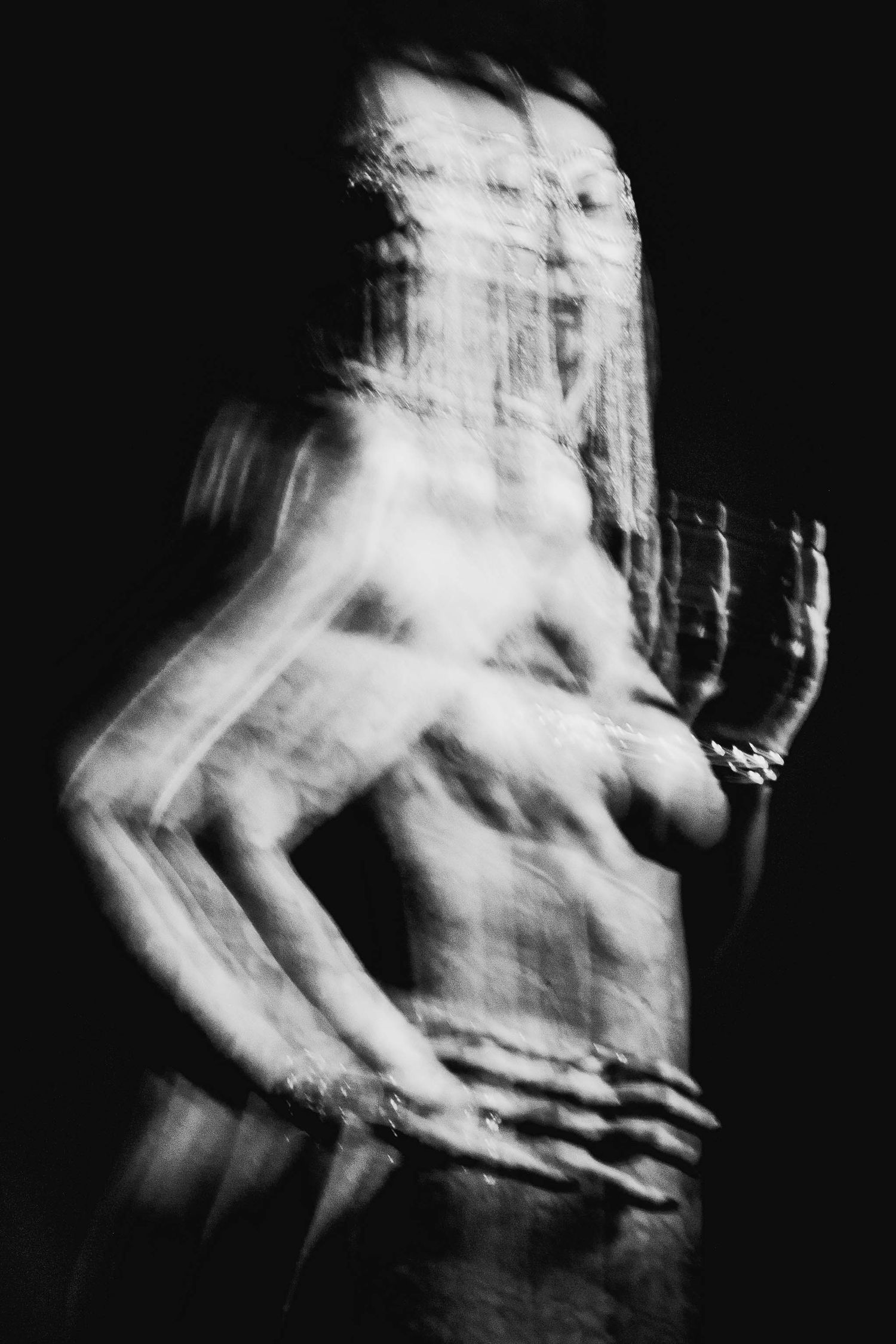 Abstract black and white long exposure photograph of tattooed woman with motion blur effect.