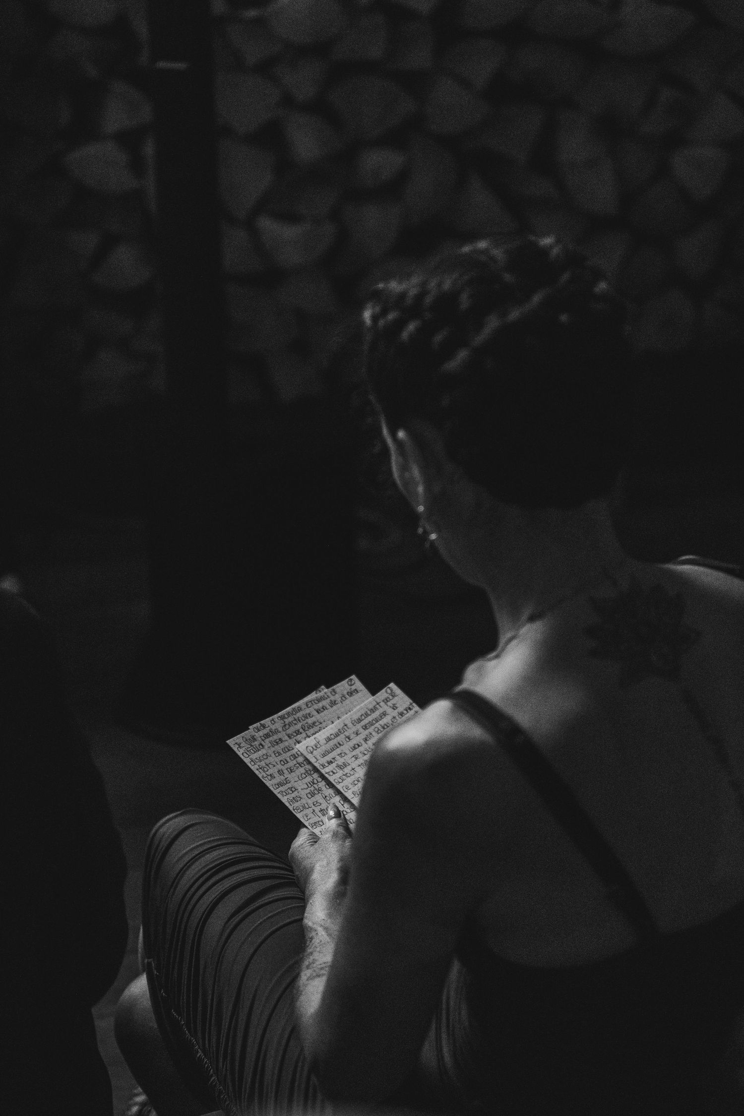 Black and white photo of tattooed woman reading handwritten notes at a wedding ceremony.