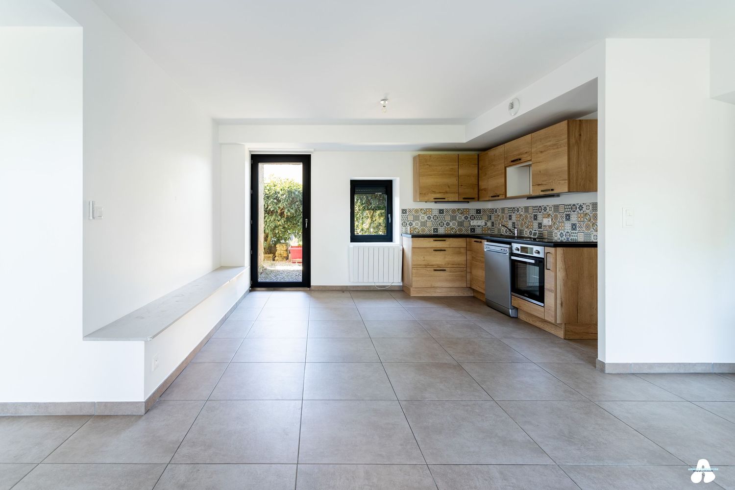 Modern kitchen with wooden cabinets, tile backsplash, and large tiled floor in open plan layout.