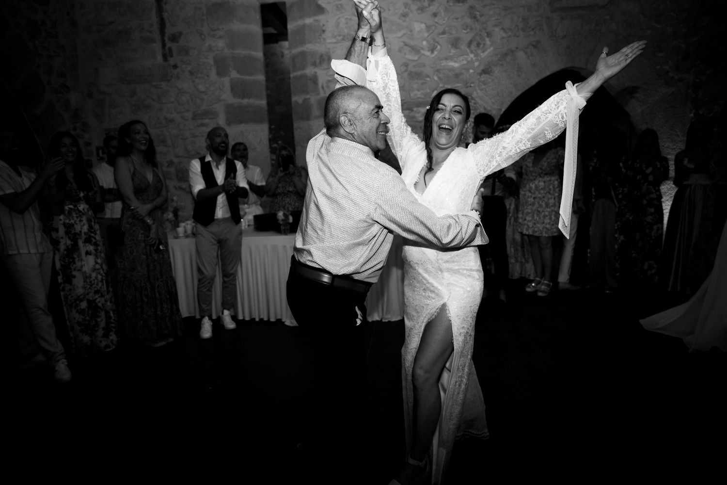 Black and white photo of a bride and guest dancing energetically at a wedding reception.