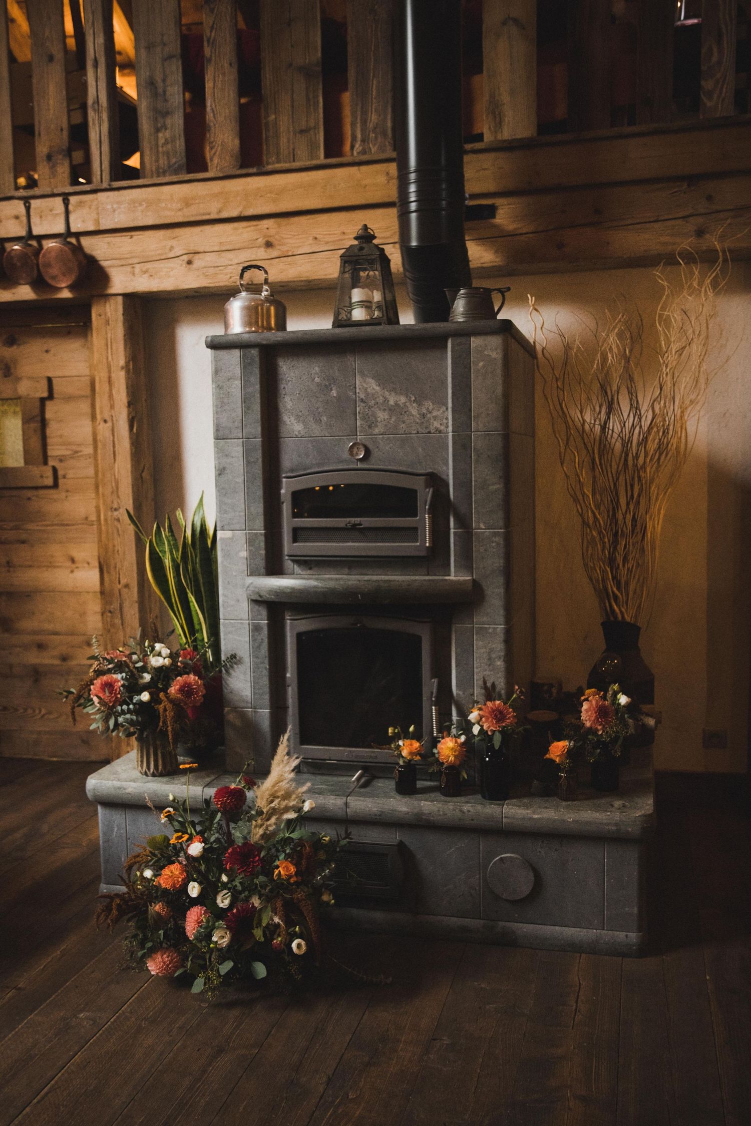 Rustic wood burning fireplace decorated with colorful floral arrangements in wooden interior.