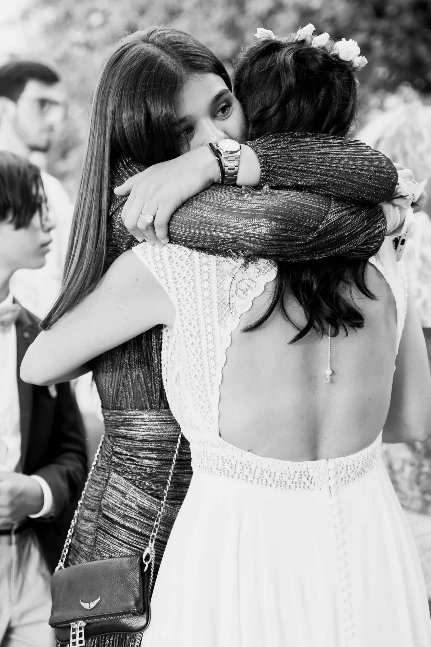 Black and white photo of a bride sharing an emotional hug with a guest at her wedding.
