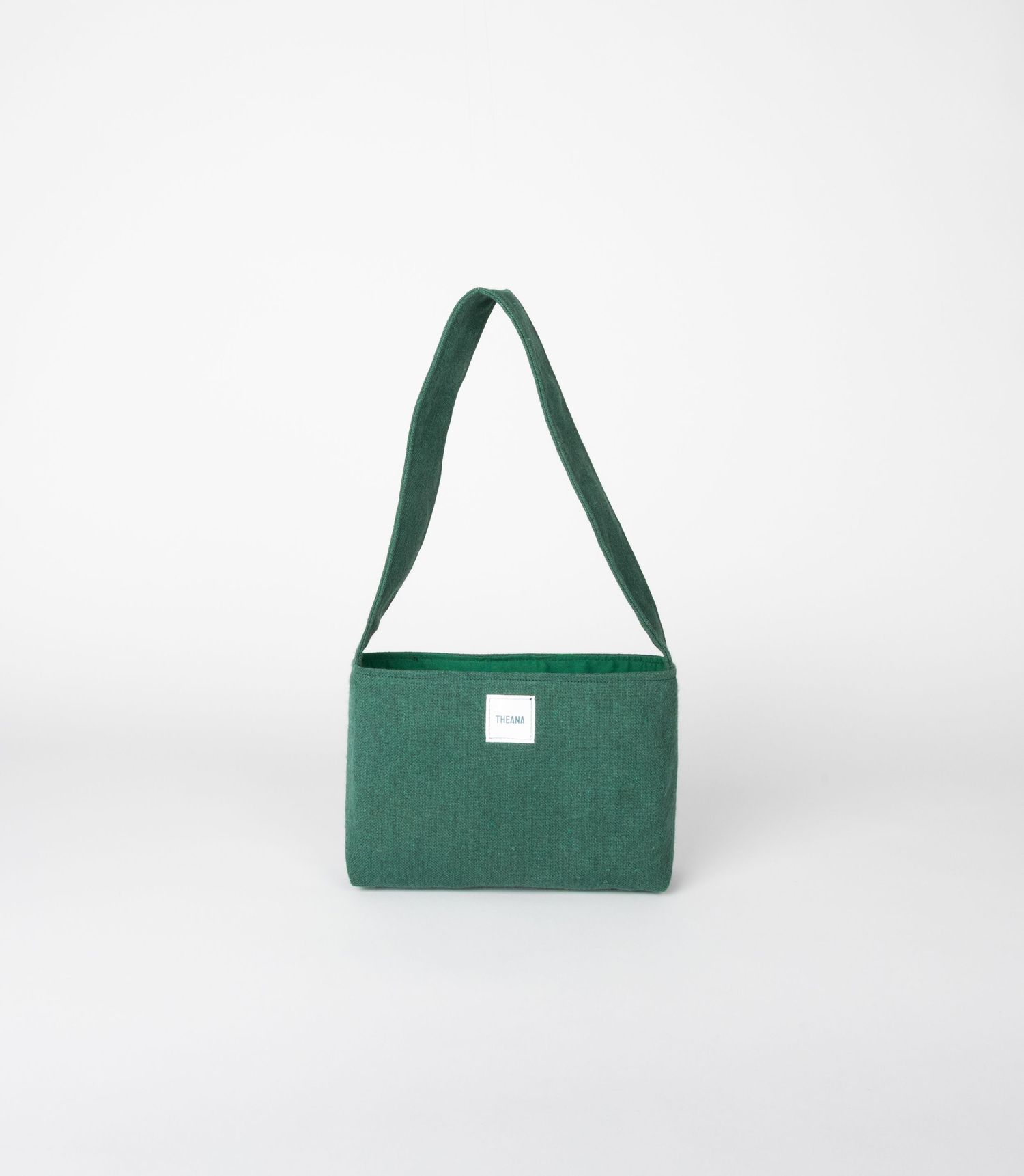 Forest green wool-blend shoulder bag with matching long flat strap and small white brand label, minimalist.
